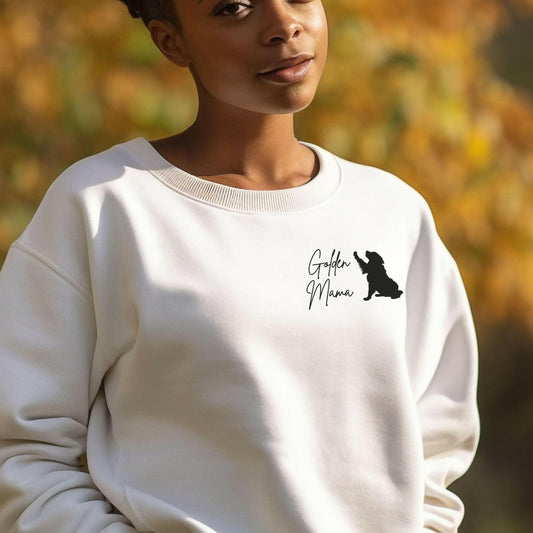 Woman smiling and wearing a white crewneck sweatshirt with the words "golden mama" and a graphic of a golden retriever dog. This comfortable oversized sweatshirt makes a a great gift for dog lovers. 
